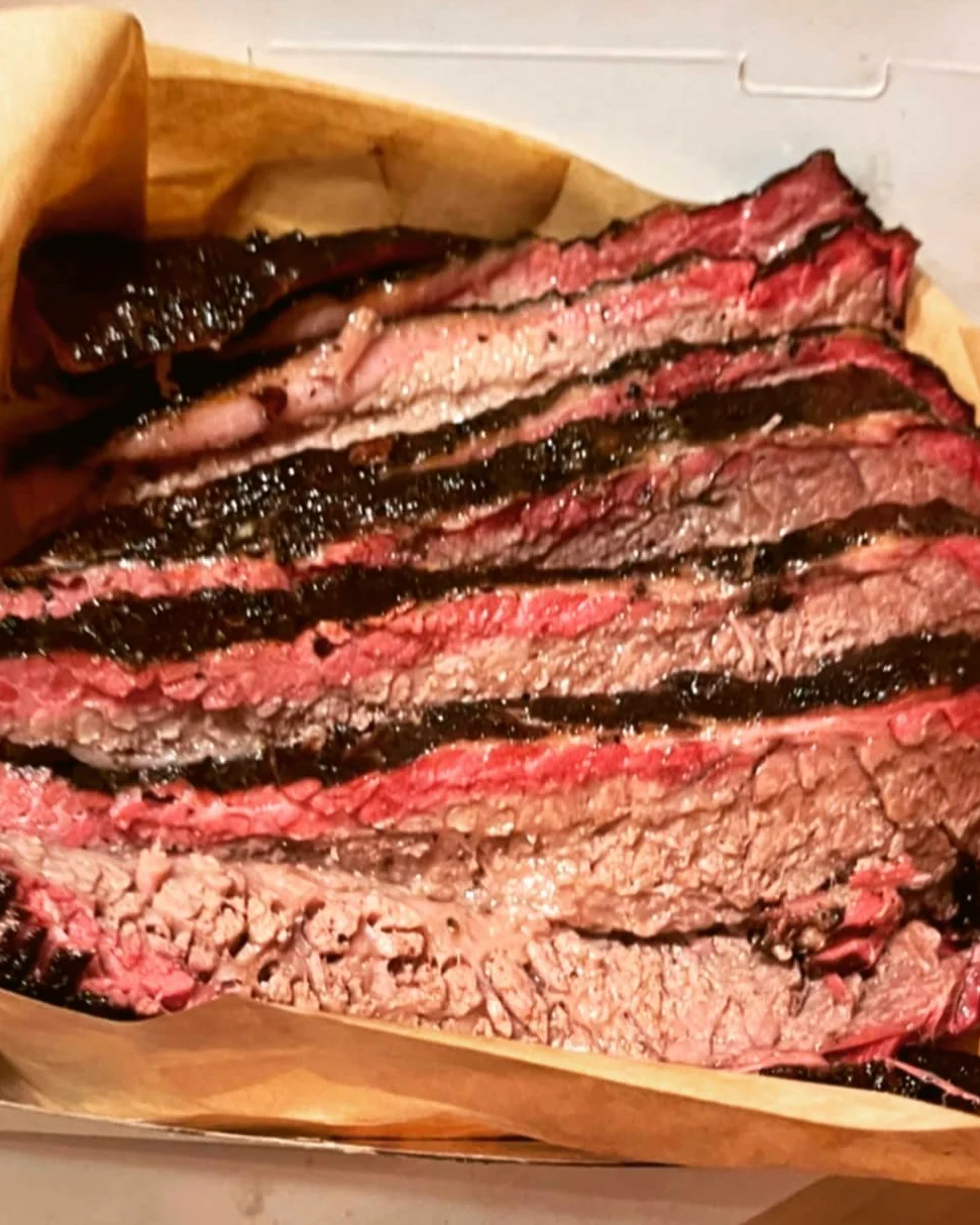 Καπνιστό brisket κομμένο σε φέτες, πάνω σε χαρτί κρεοπωλείου, με εμφανές smoke ring